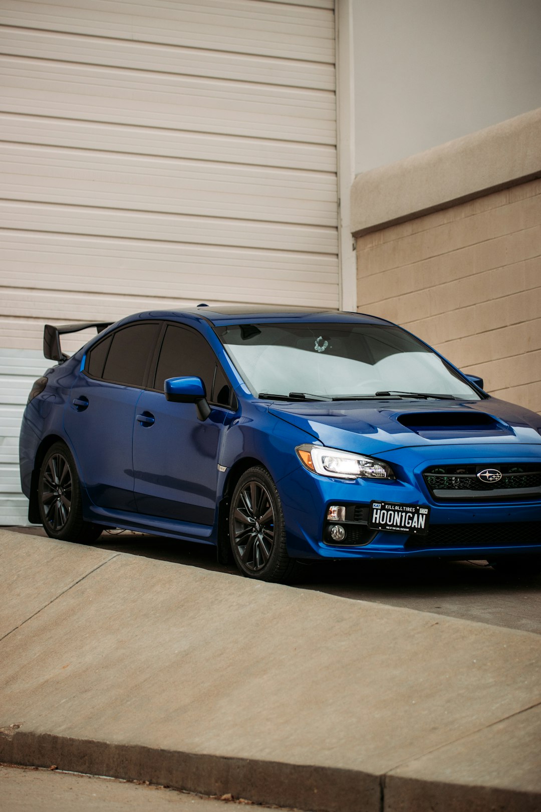 blue honda car parked beside white wall