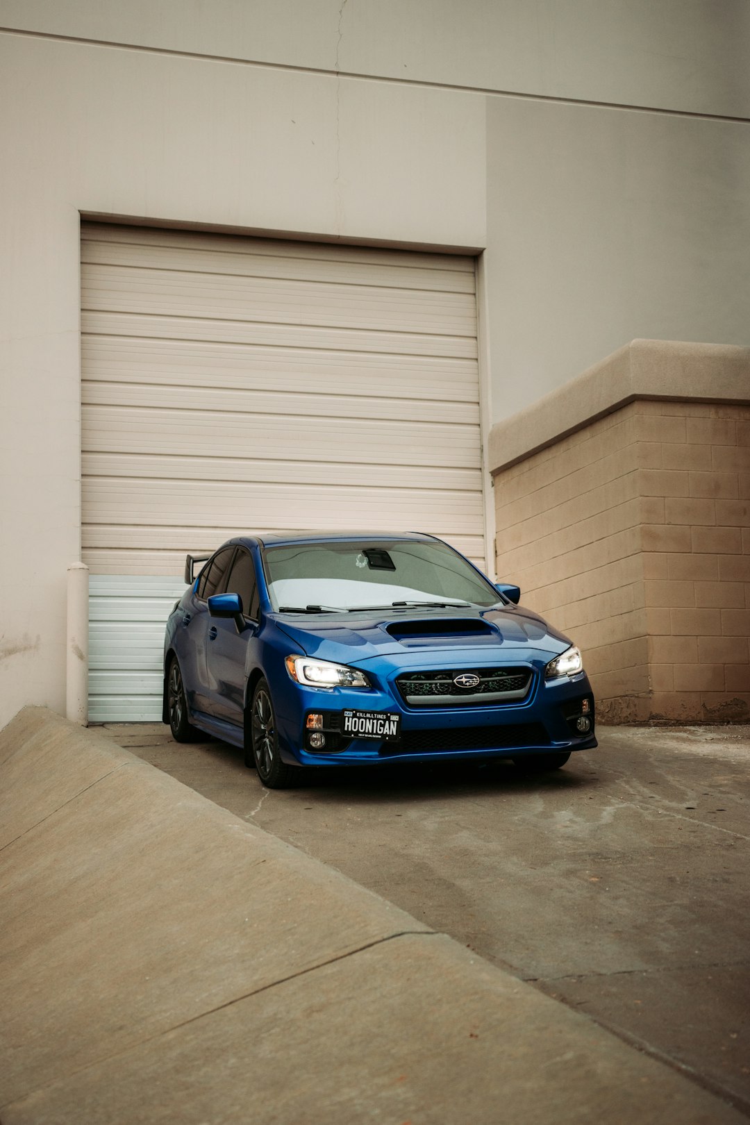 blue bmw m 3 coupe parked beside white garage door
