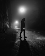 A cinematic scene showing a shadowy figure in a foggy street.