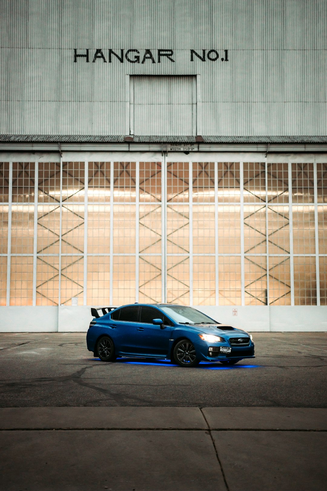 blue sedan parked beside white wall