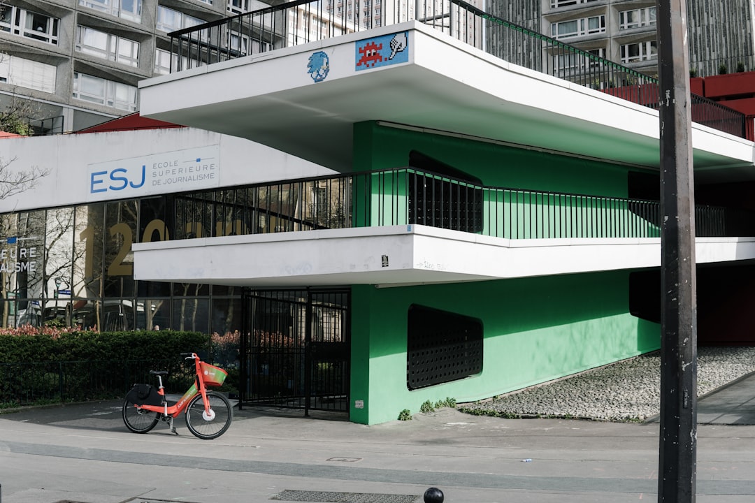 red bicycle parked beside green concrete building during daytime