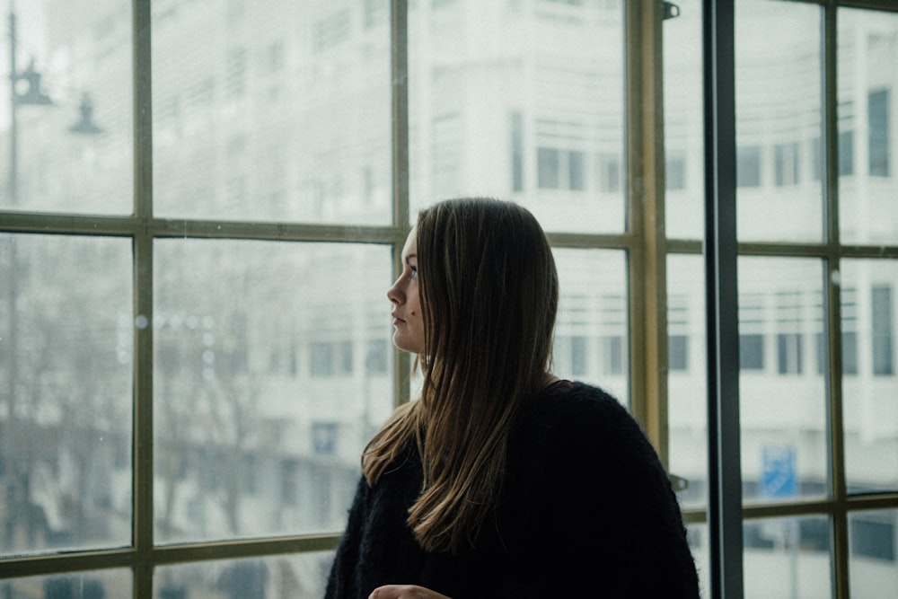 woman in black long sleeve shirt standing near glass window