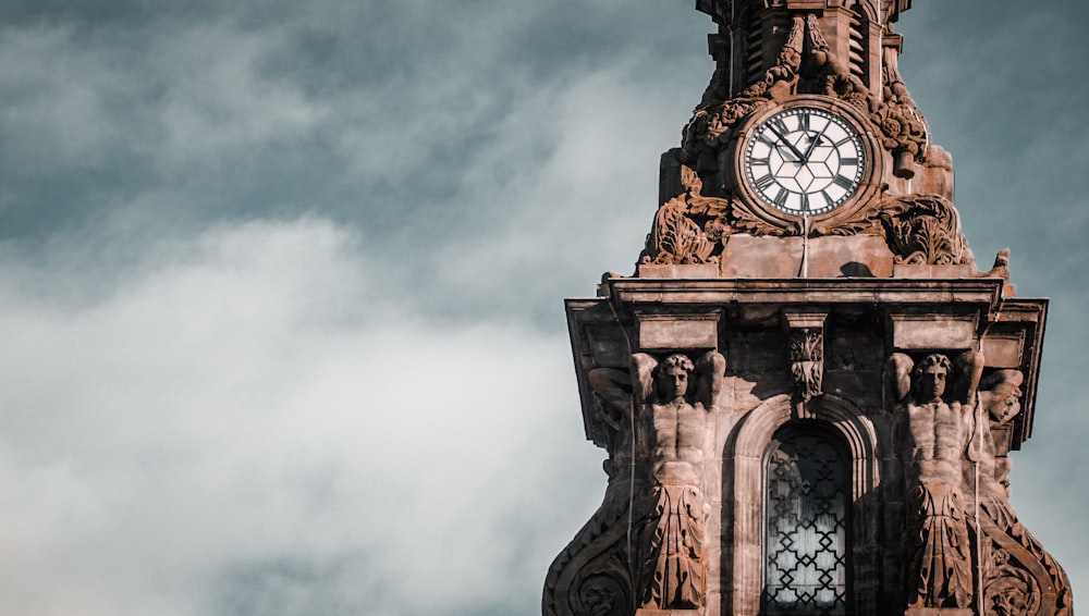 Brauner Betonuhrturm unter weißen Wolken