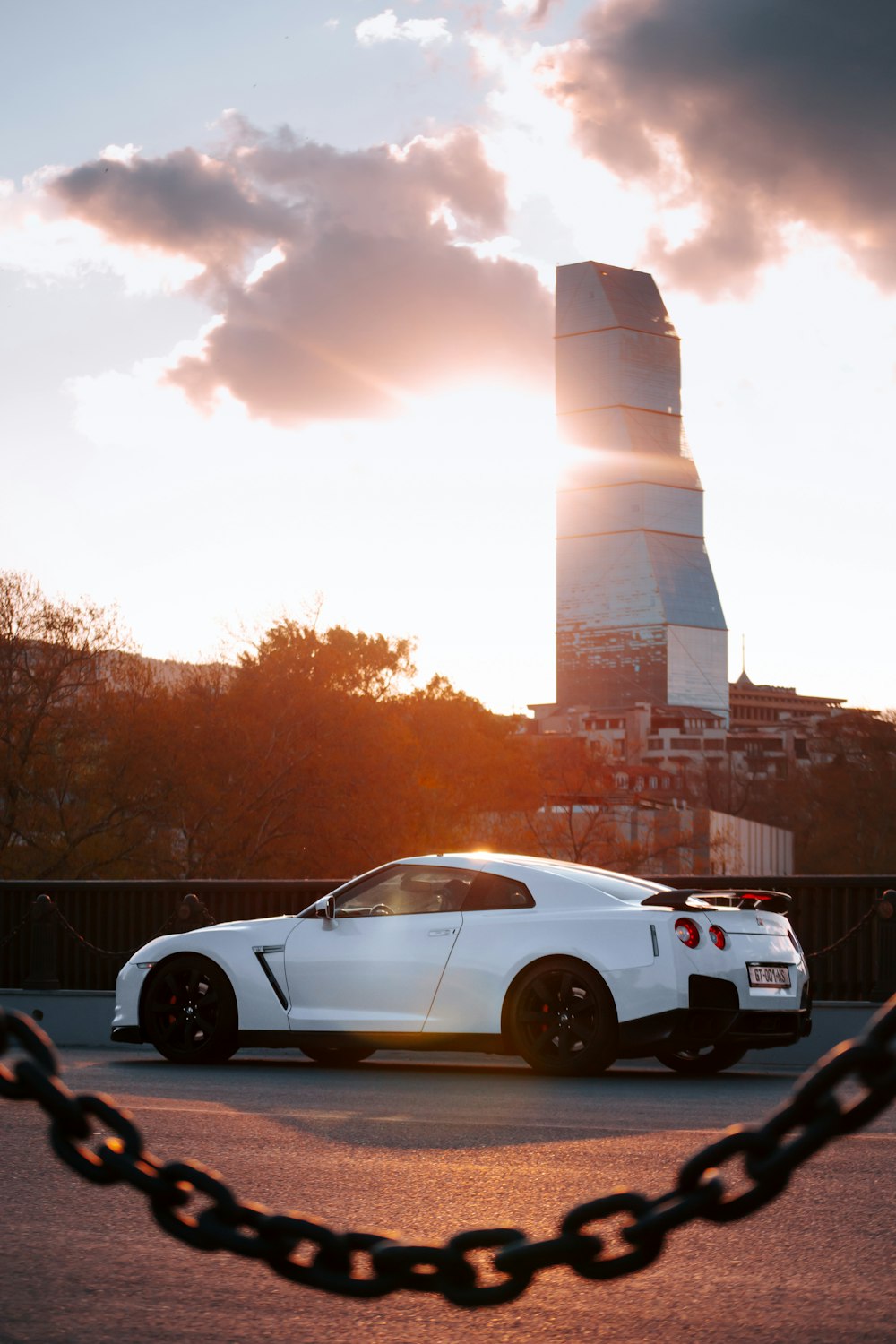 white coupe parked beside brown concrete building during daytime