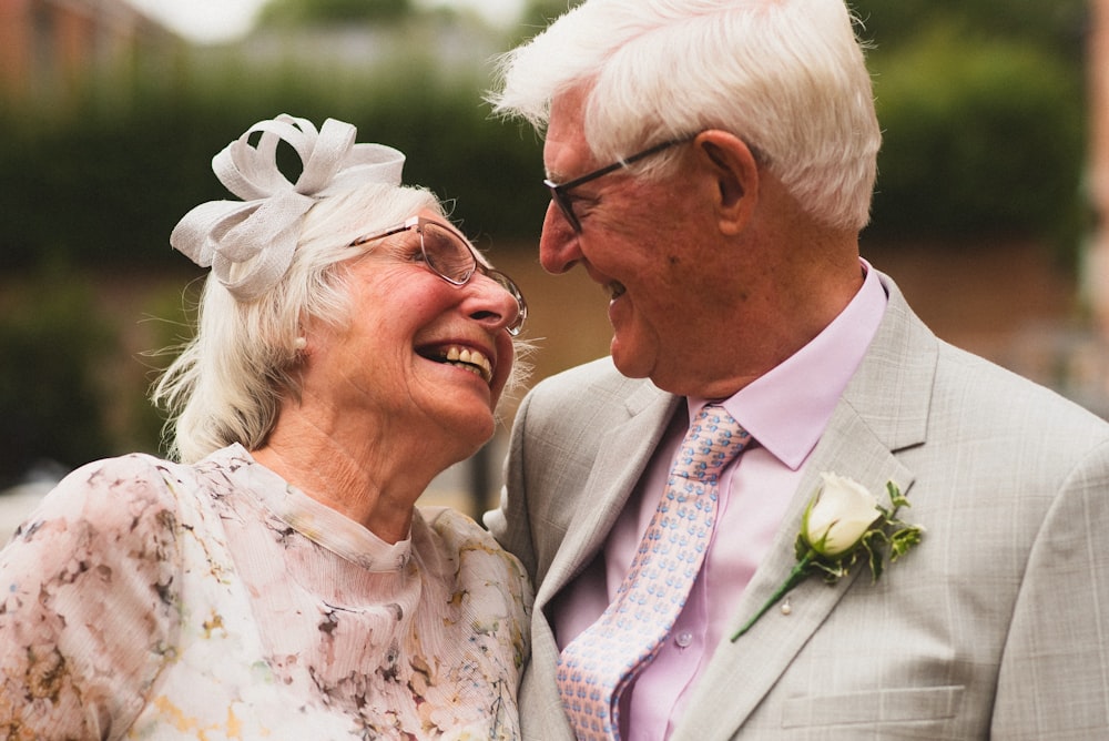 man in gray suit jacket beside woman in white floral dress