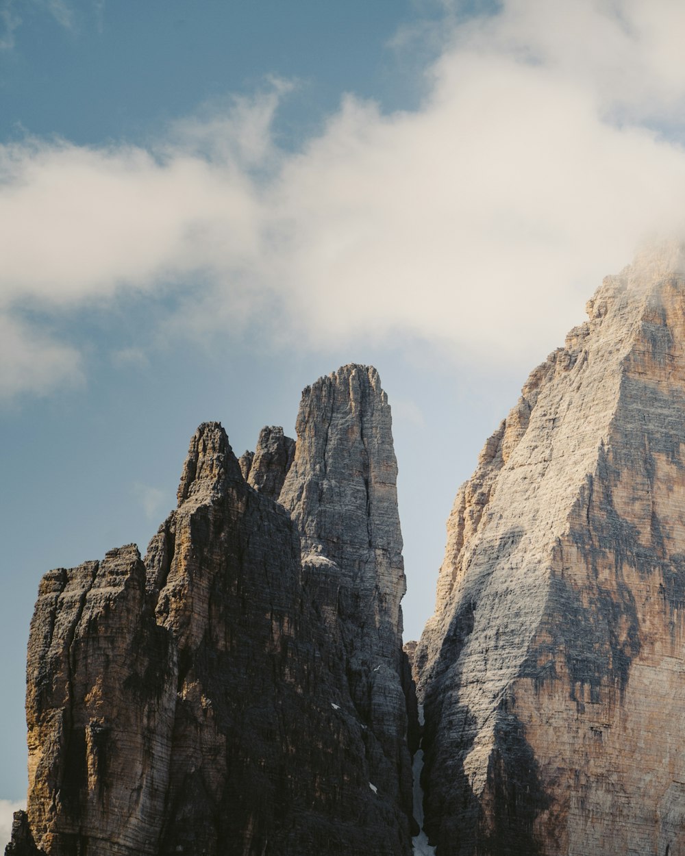 Montagne rocheuse brune sous des nuages blancs pendant la journée