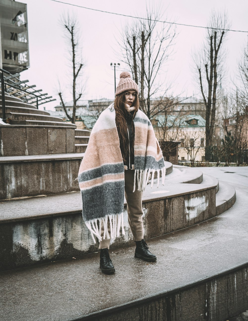 Femme en foulard blanc, rouge et bleu debout sur un pont en béton gris pendant la journée