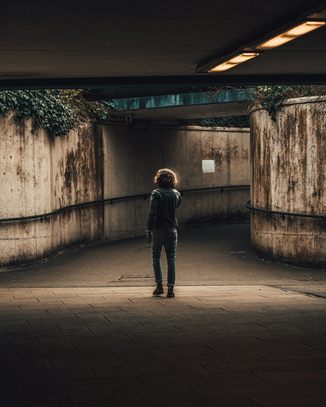 man in black jacket and black pants standing on gray concrete floor