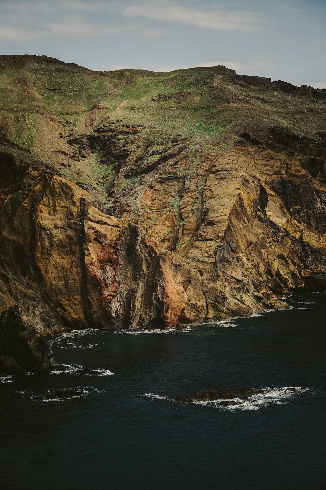 brown and green mountain beside body of water during daytime