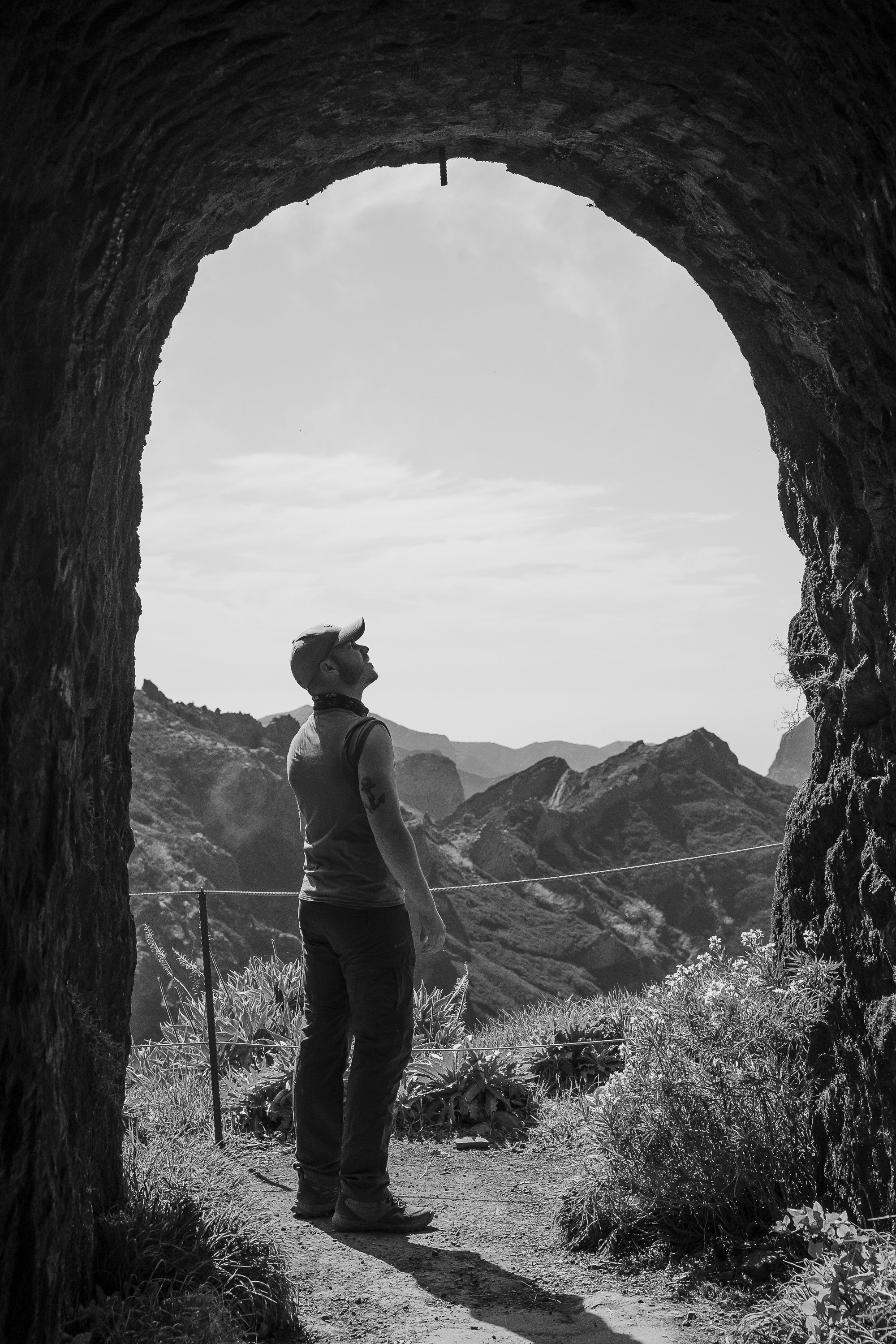 man in gray shirt and black pants standing on rock formation during daytime