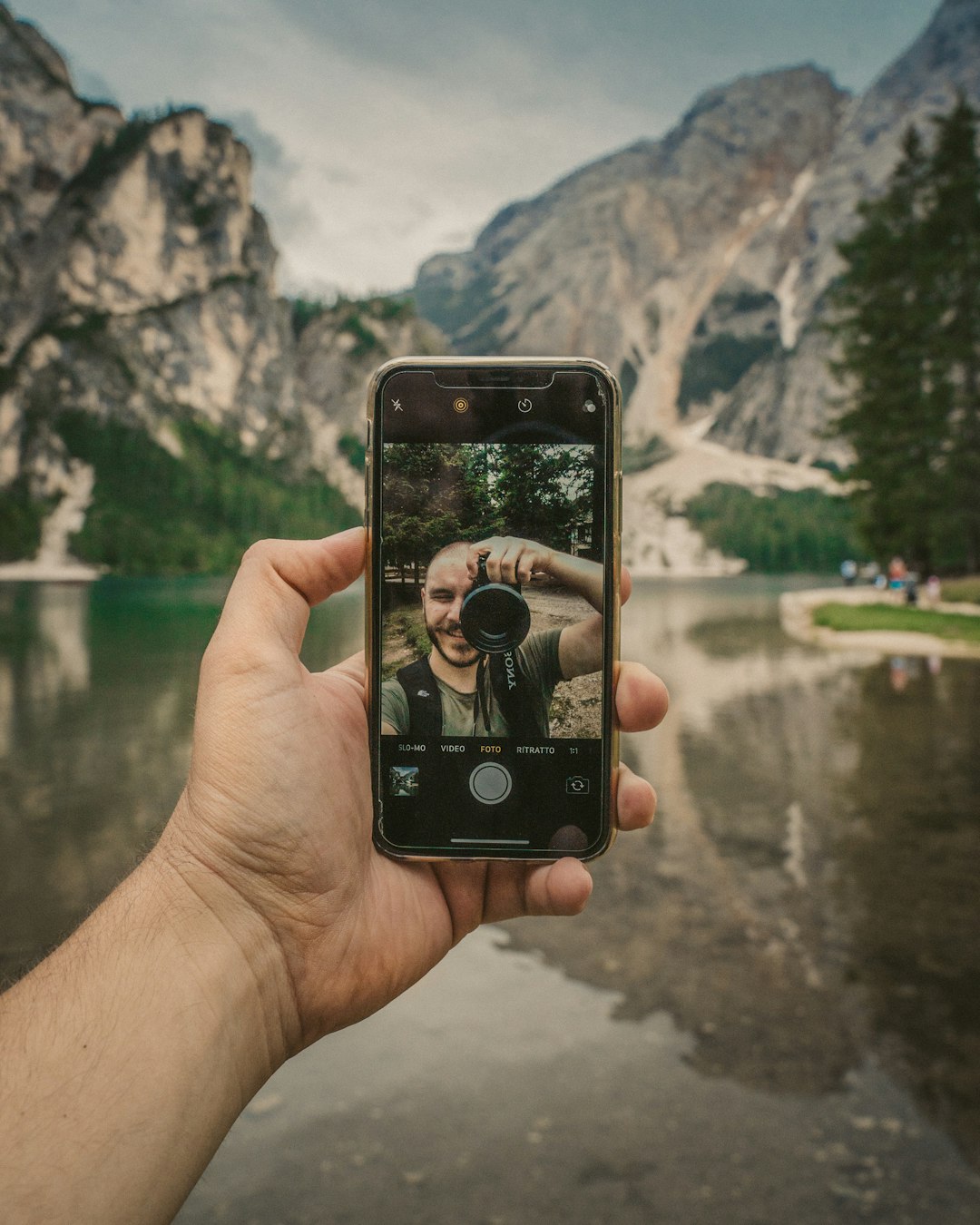 person holding black iphone 4 taking photo of green trees during daytime