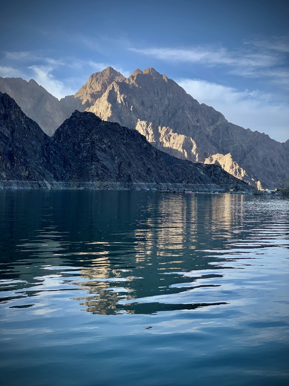 blue body of water near mountain during daytime