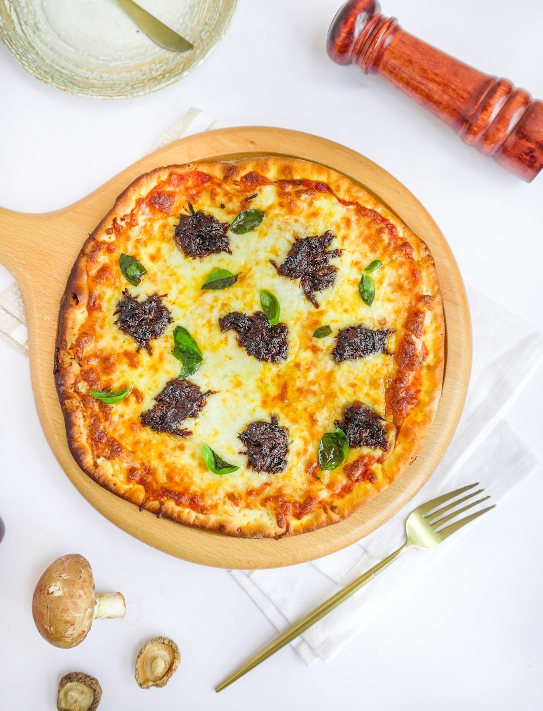 pizza with green leaves on brown wooden round plate