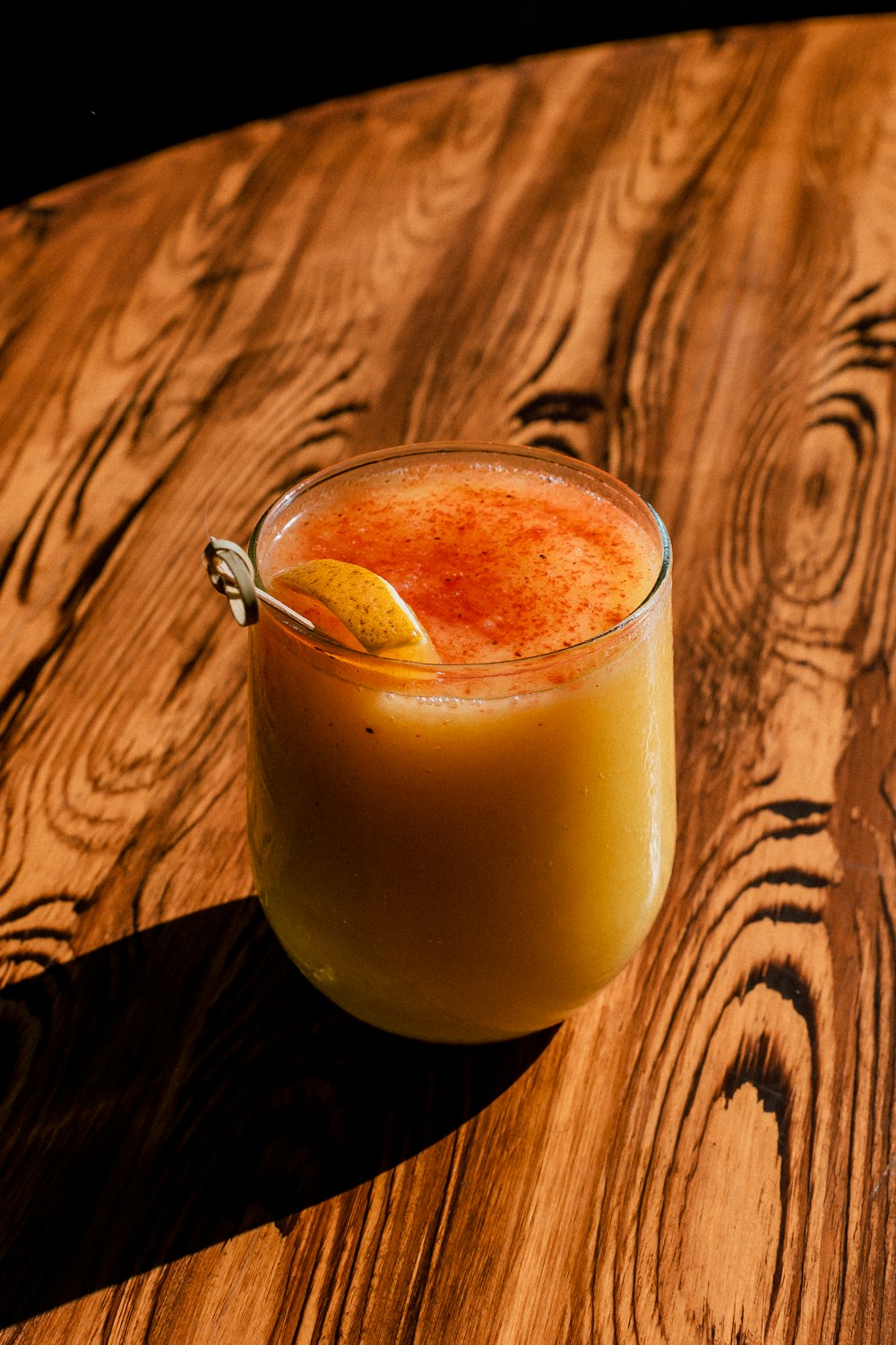 clear drinking glass with yellow liquid on brown wooden table