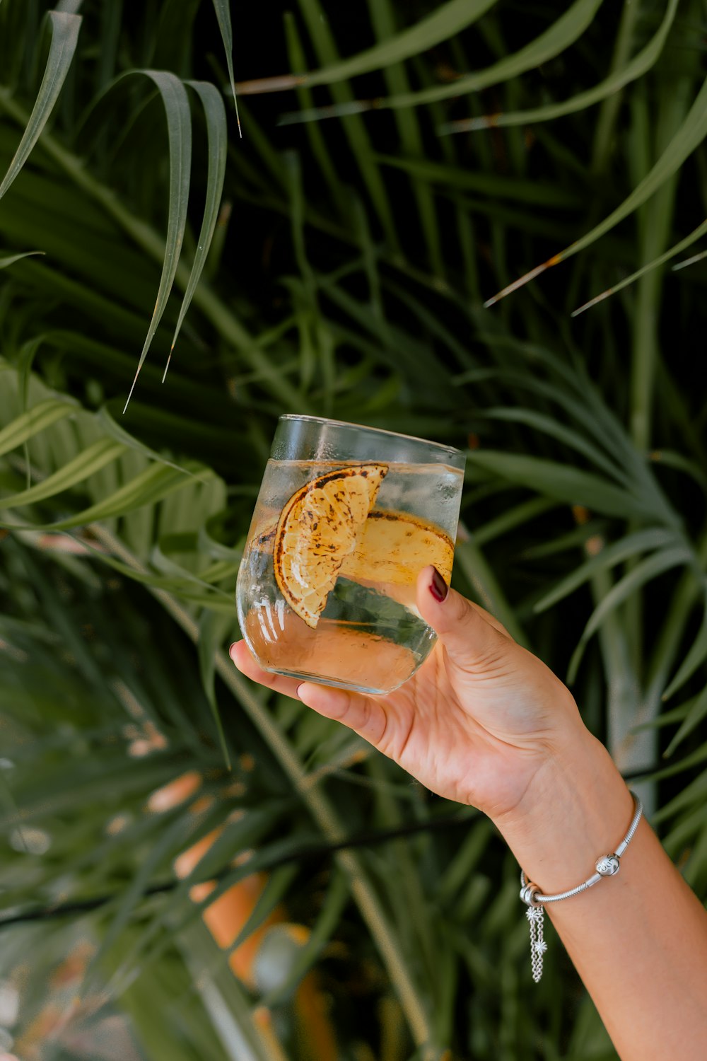 person holding clear drinking glass with brown liquid