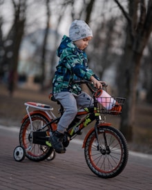 child in green and black camouflage jacket riding on bicycle