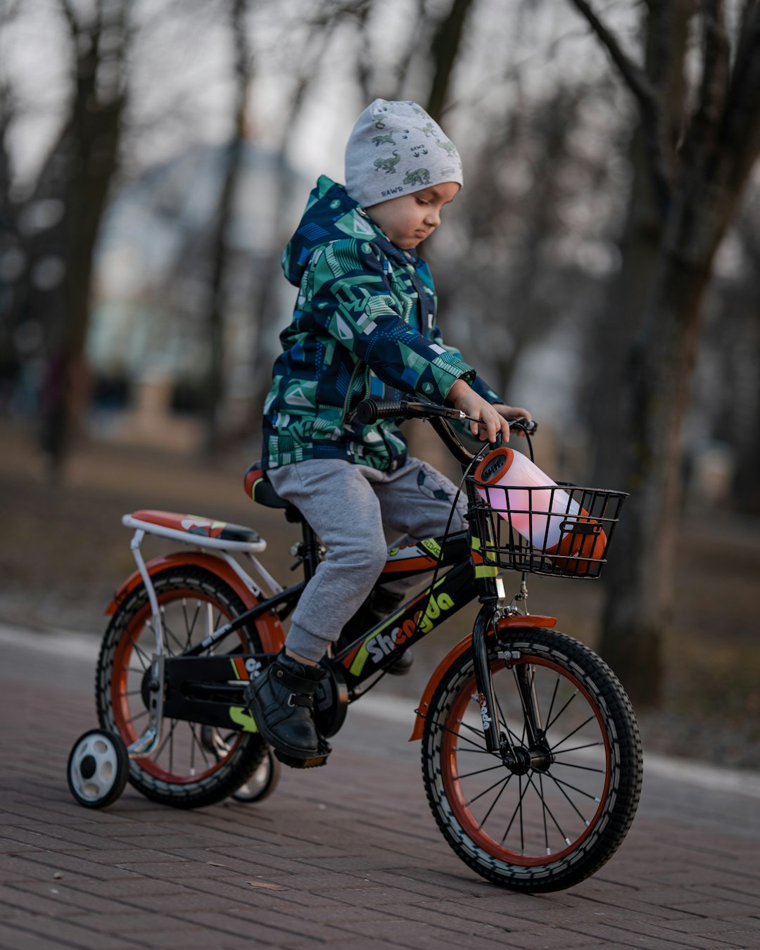 child in green and black camouflage jacket riding on bicycle