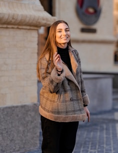 A woman in a premium, warm jacket smiling confidently against a winter city backdrop