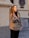 A smiling woman wearing stylish casual clothes in a bright urban setting.
