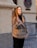 A smiling woman wearing stylish casual clothes in a bright urban setting.