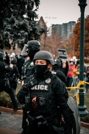 man in black helmet and black jacket standing near people during daytime