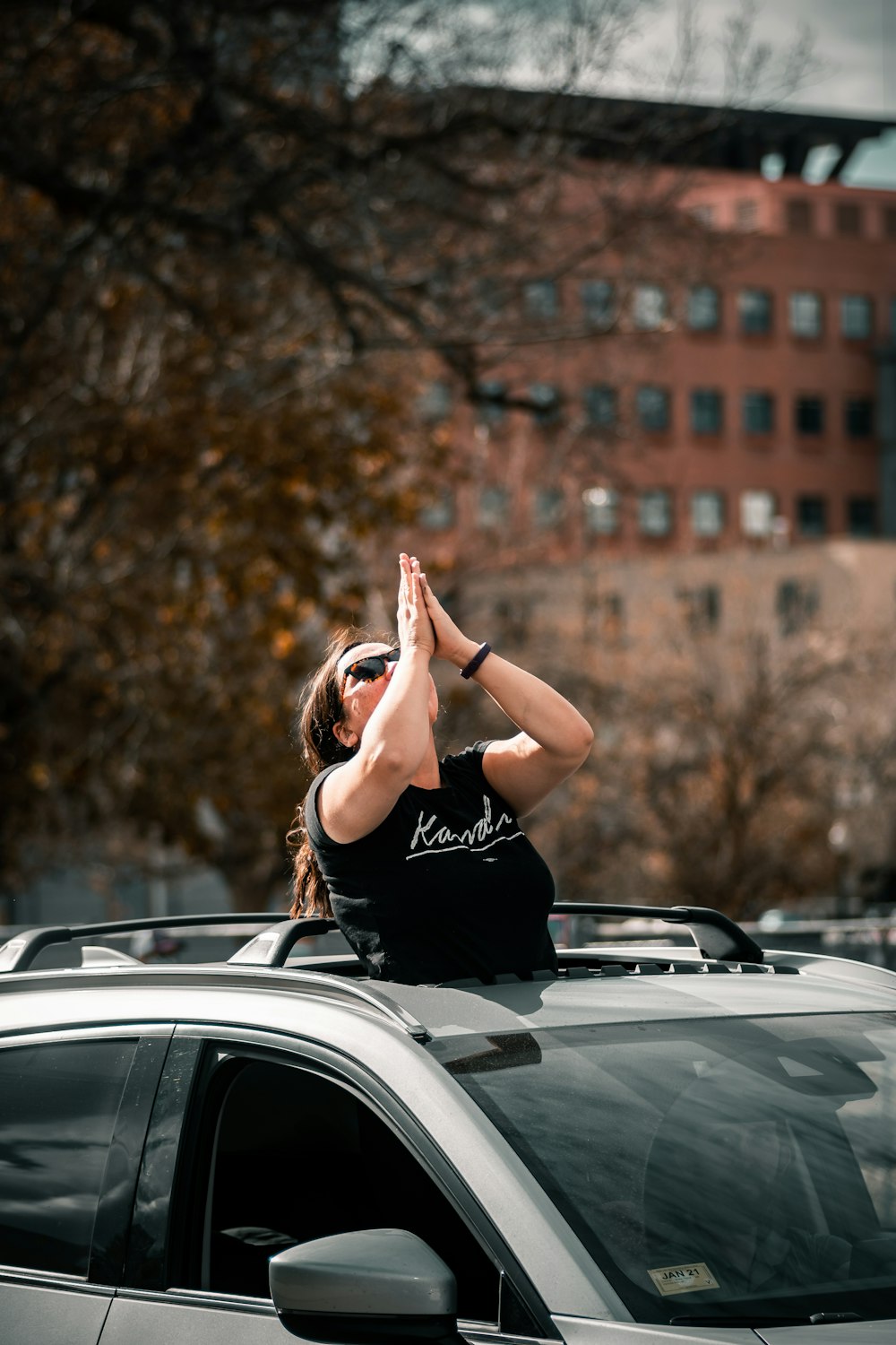 woman in black t-shirt sitting on car hood during daytime