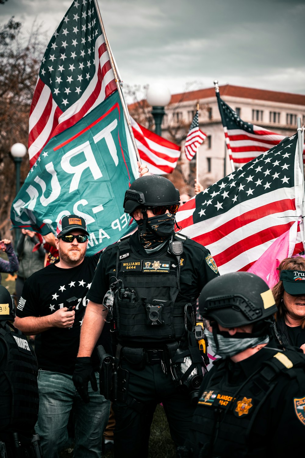 Hombre con uniforme negro de policía sosteniéndonos una bandera