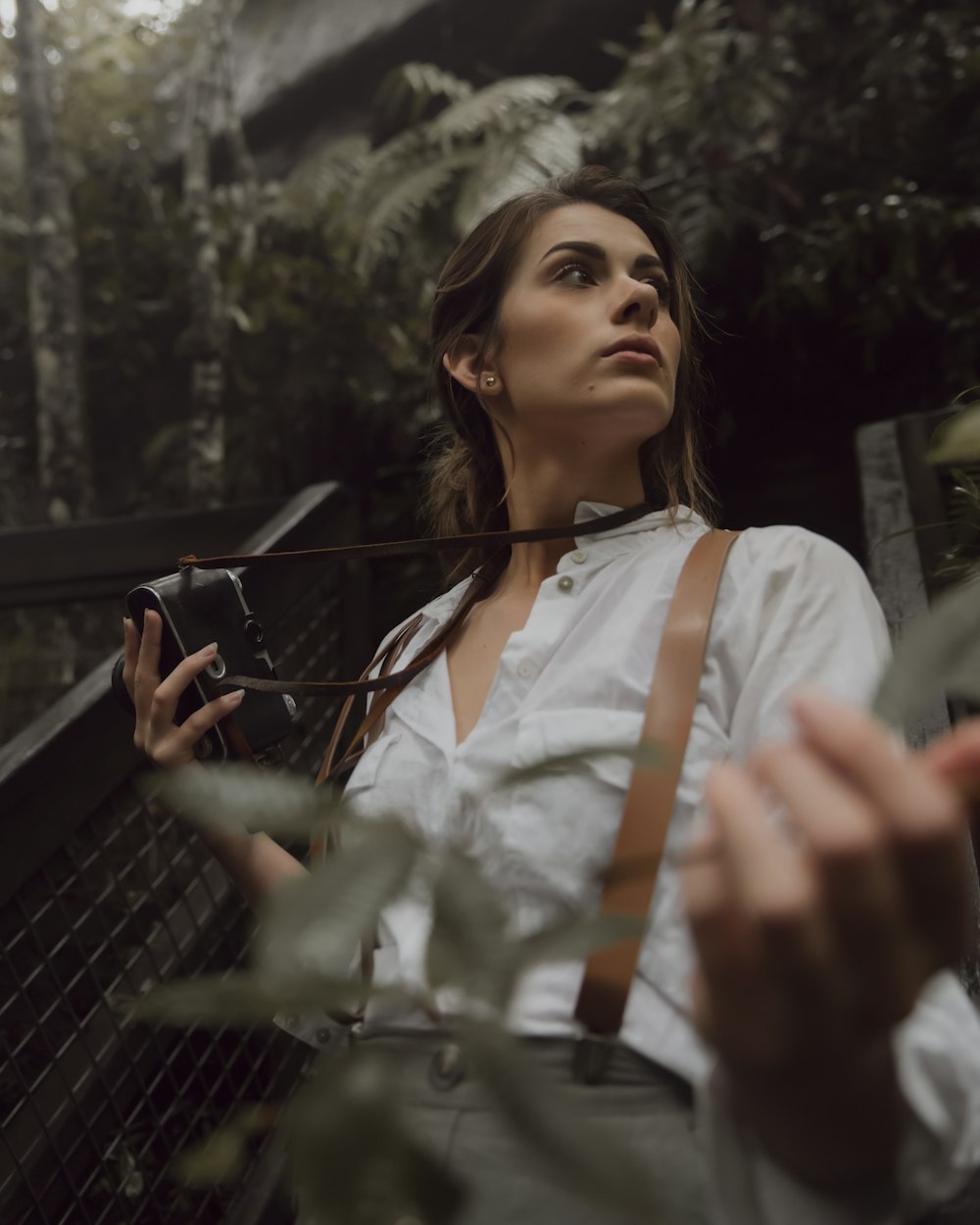 woman in white dress shirt holding black metal fence