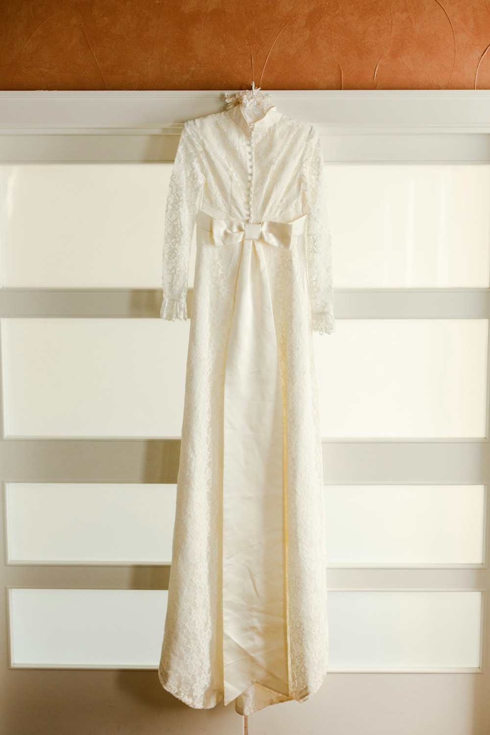 white long sleeve dress hanged on white wooden rack