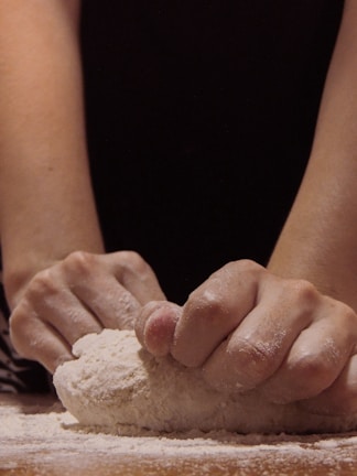 A close-up of a baker’s hands shaping dough with care in the bakery kitchen.