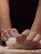 Hands kneading dough on a flour-dusted surface, focusing on the act of making bread or pastry. The texture of the dough and flour is visible, with arms positioned against a dark background.