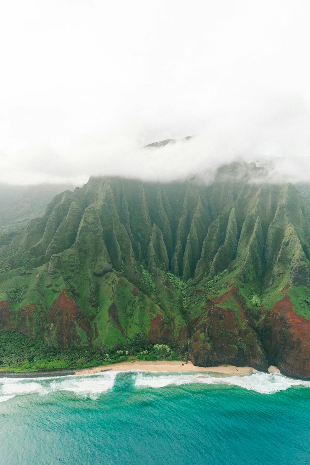 montaña verde y marrón bajo el cielo blanco durante el día