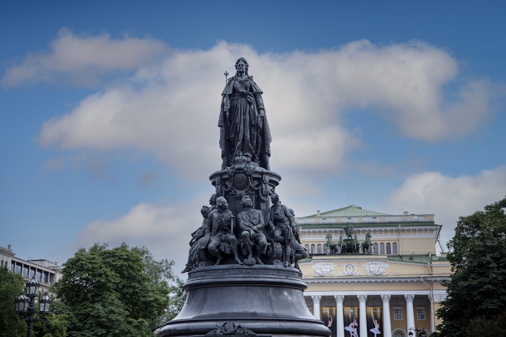 gray concrete statue near green trees under white clouds during daytime