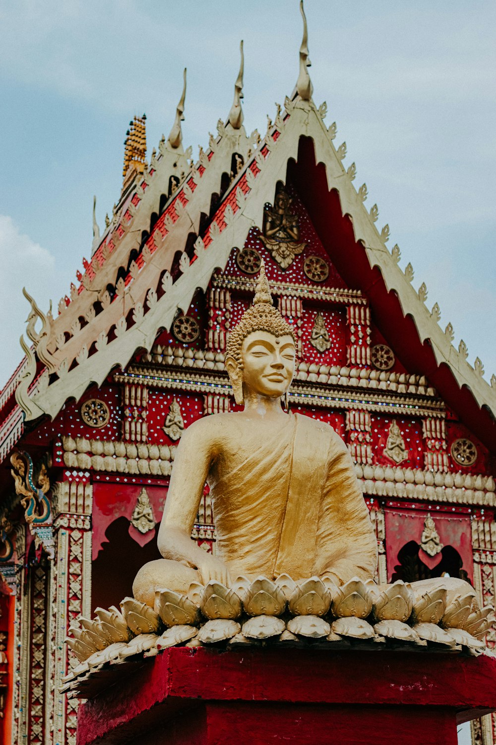 gold buddha statue near red and gold temple during daytime