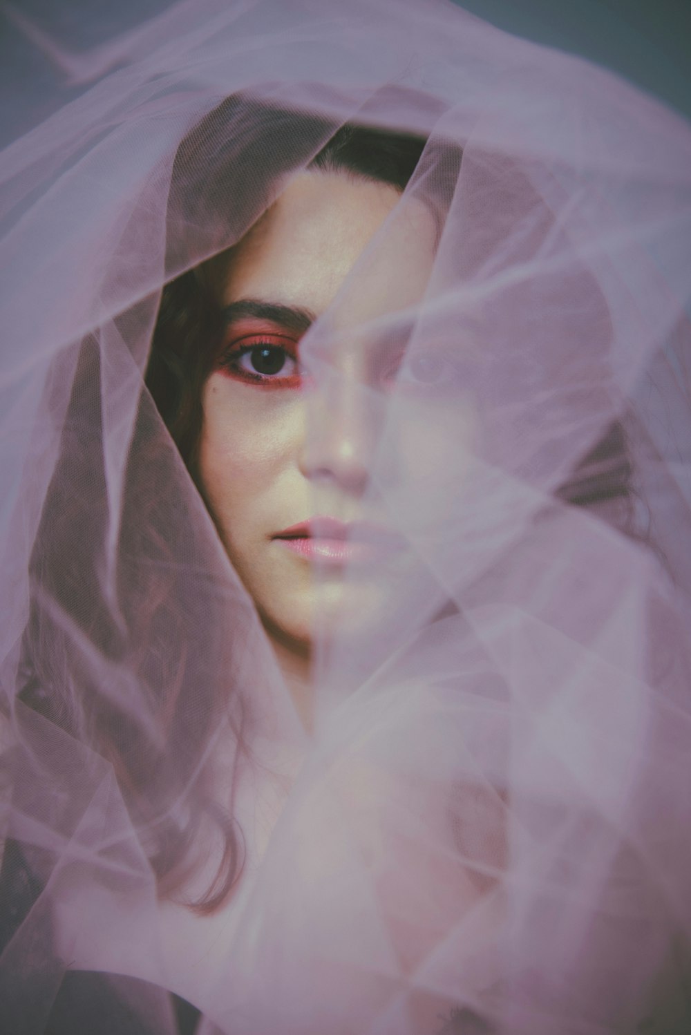 woman in white hijab covering her face with white sheer textile