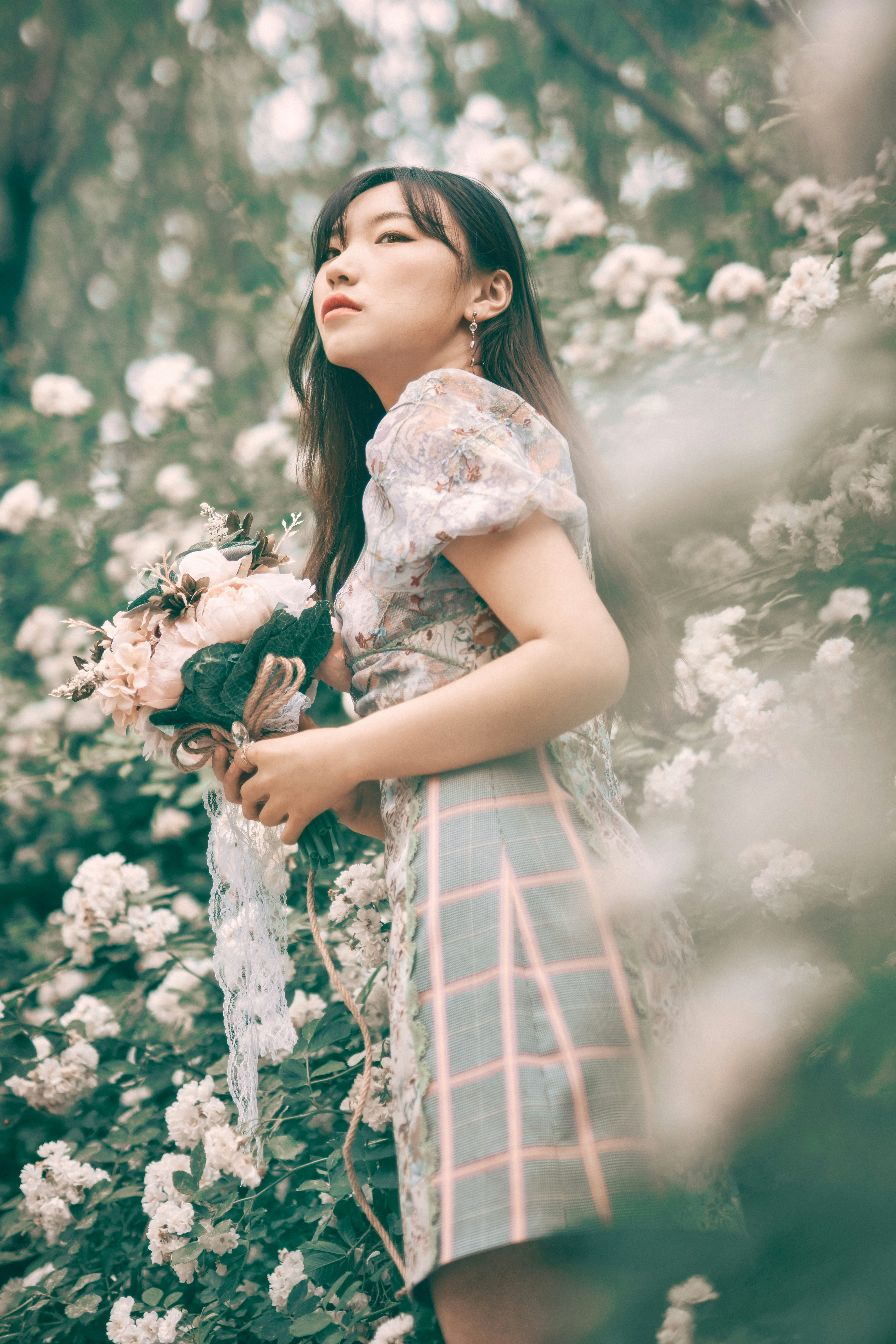 woman in blue and white plaid dress holding bouquet of flowers