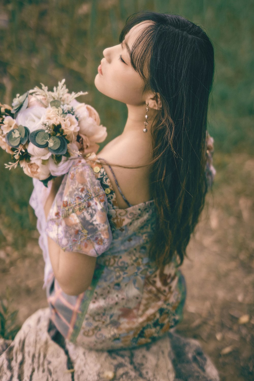 woman in white and green floral dress holding white flower