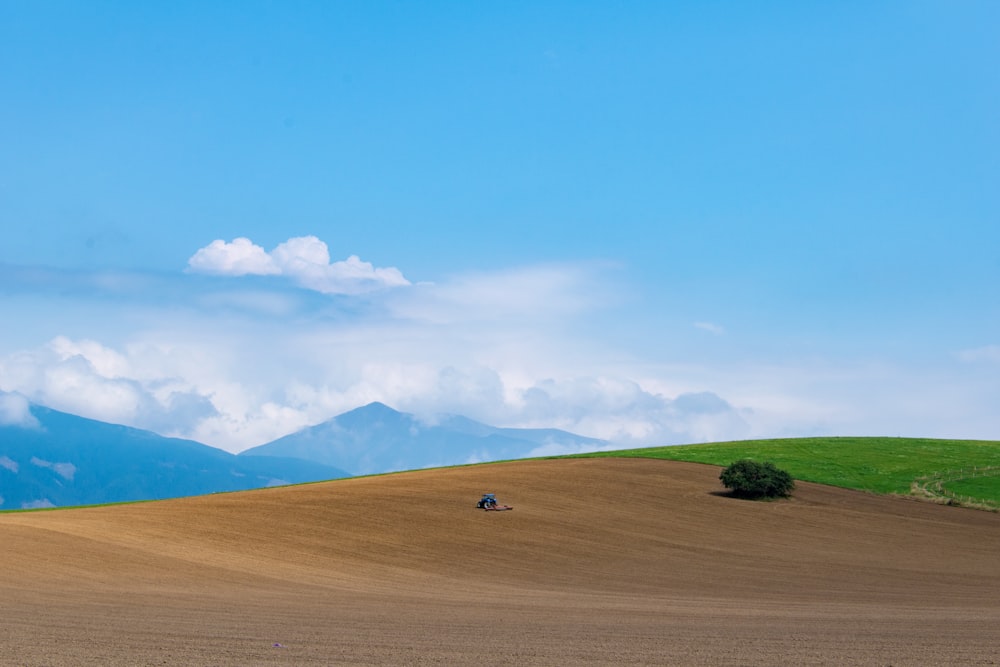 campo de hierba verde cerca de la montaña bajo el cielo azul durante el día