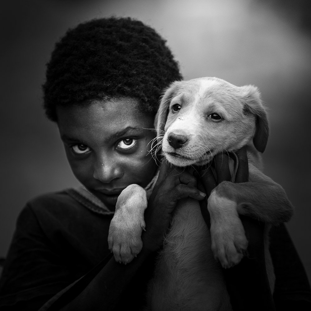 grayscale photo of man hugging dog