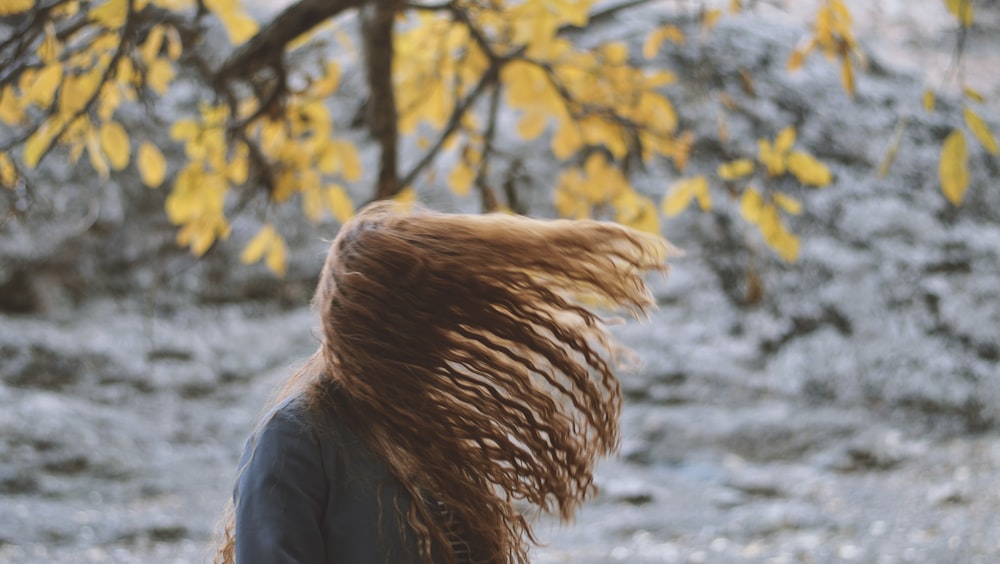 woman in gray jacket standing near yellow leaf tree during daytime