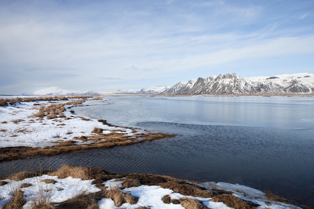 snow covered mountain near body of water during daytime