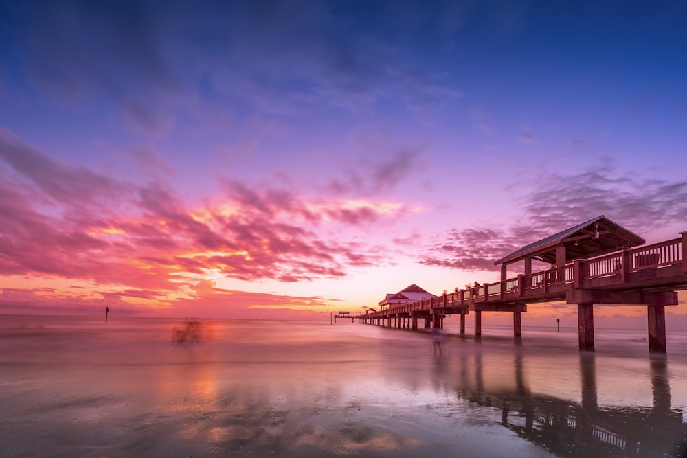 brown wooden dock on body of water during sunset