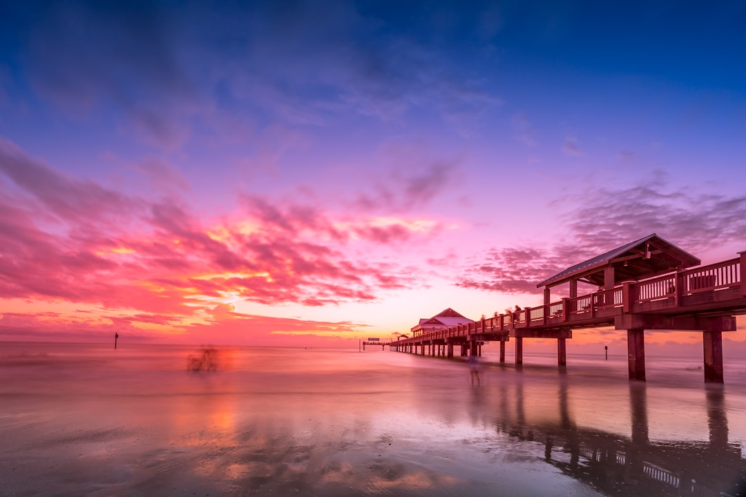 brown wooden dock on body of water during sunset