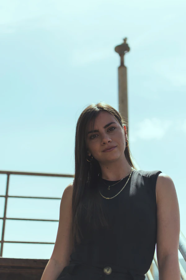 A woman by a railing under a light blue sky
