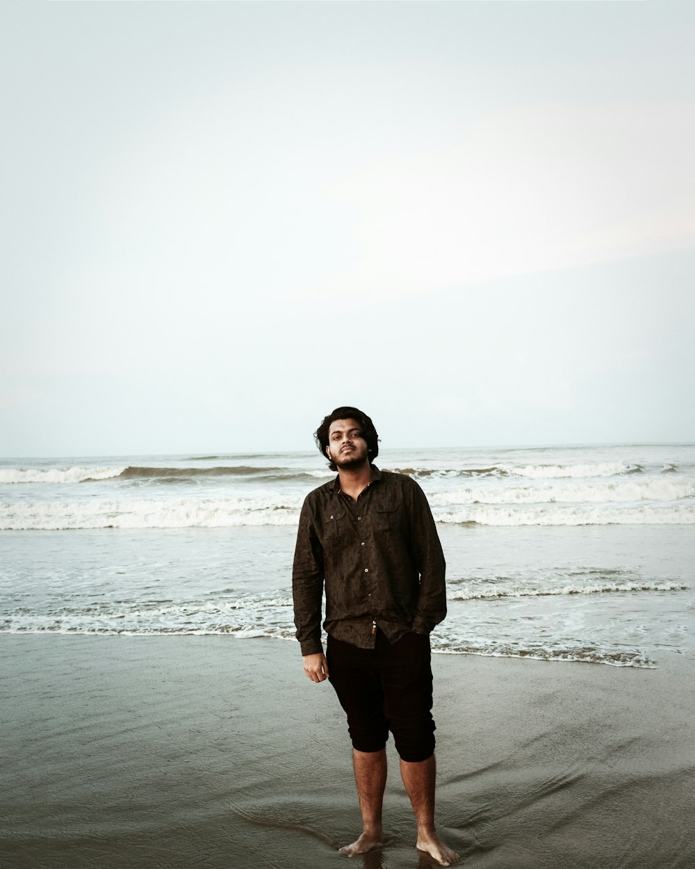 man in black jacket standing on beach