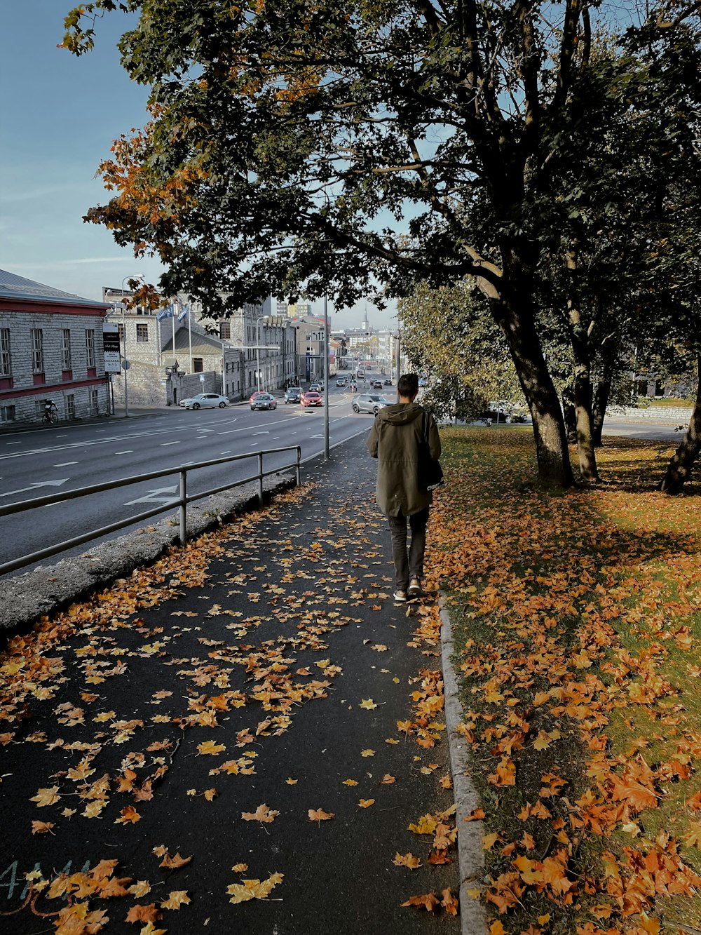 woman in brown coat walking on sidewalk during daytime