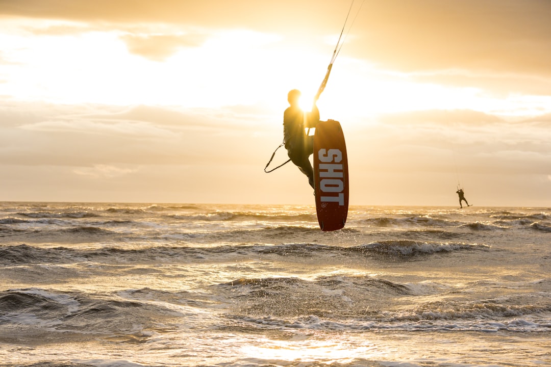 man in black wet suit holding fishing rod on sea during daytime