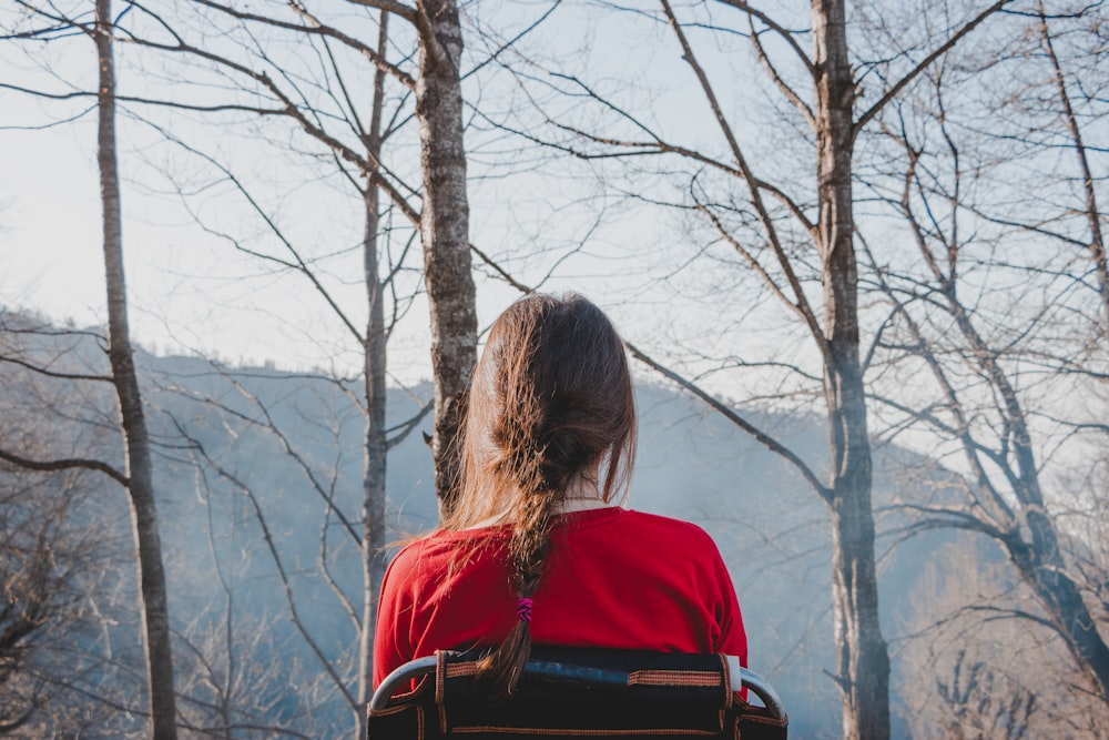 woman in red shirt standing near bare tree during daytime