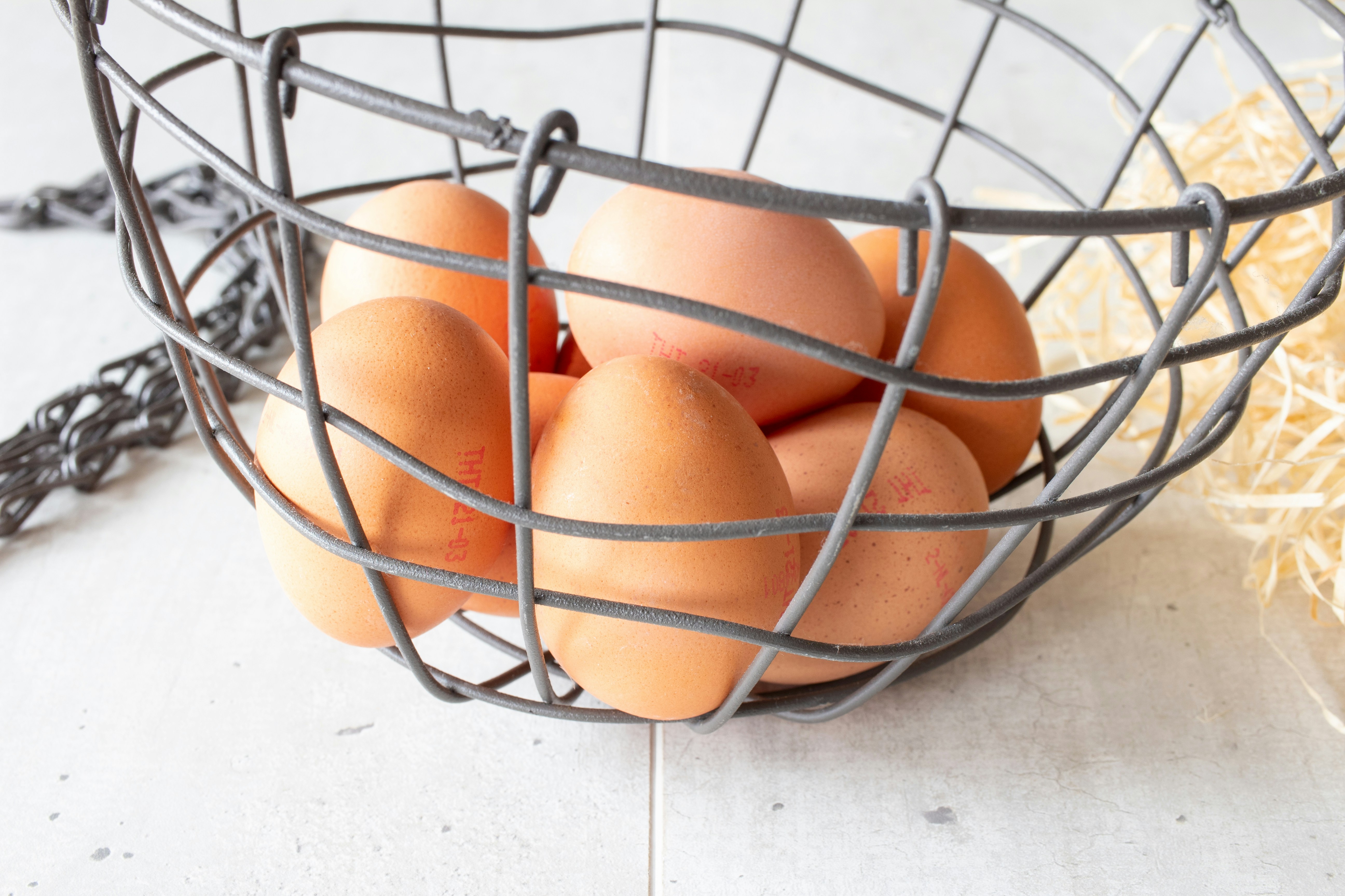 Freshly collected brown eggs in a wire basket on a bright airy farm setting, natural daylight