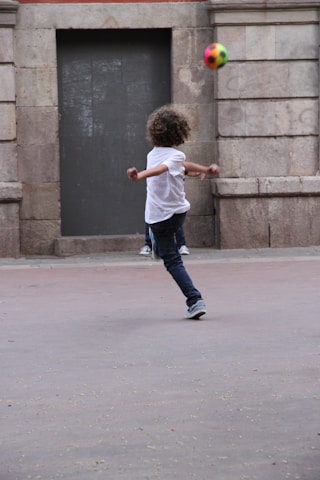 A vibrant urban scene showing a young person wearing Three Kick apparel while playing street football.